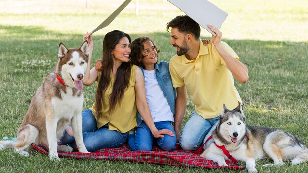 Familia sonriente con perros pasar tiempo juntos en el parque