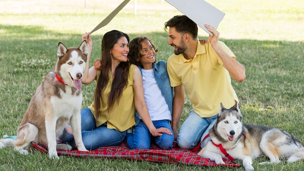 Familia sonriente con perros pasar tiempo juntos en el parque
