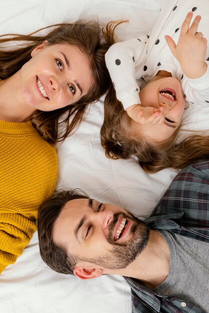 Familia sonriente de primer plano en la cama