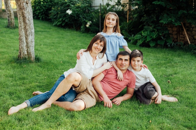 Familia sonriente que se sienta en hierba en el aire libre