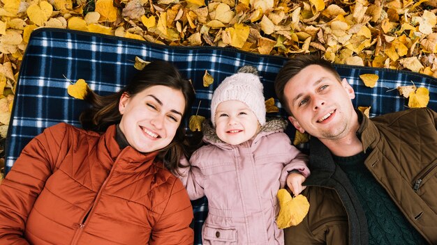 Familia sonriente tendida en el parque de otoño