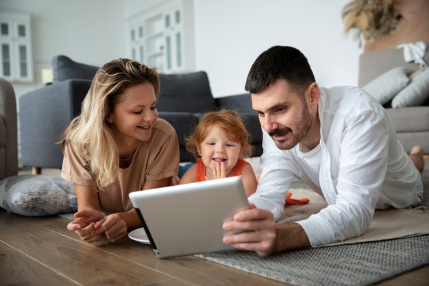 Familia sonriente de tiro completo con tableta