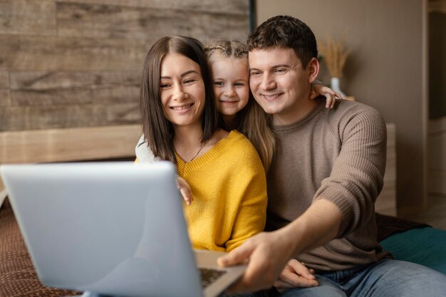 Familia sonriente de tiro medio con laptop