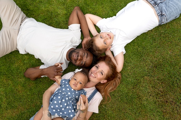 Familia sonriente de tiro medio sobre el césped