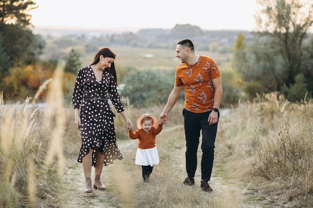 Familia con su pequeña hija en un campo de otoño