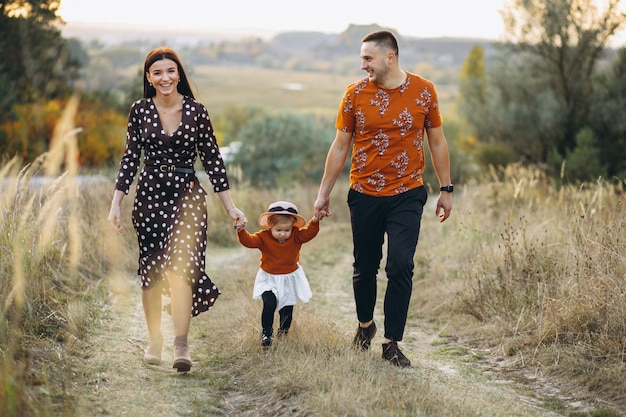 Foto gratuita familia con su pequeña hija en un campo de otoño