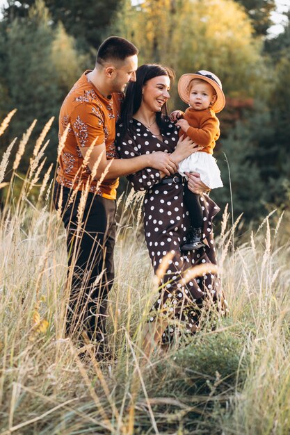 Familia con su pequeña hija en un campo de otoño