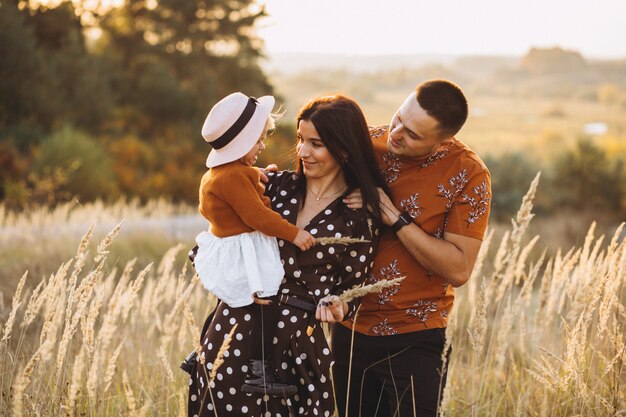 Familia con su pequeña hija en un campo de otoño