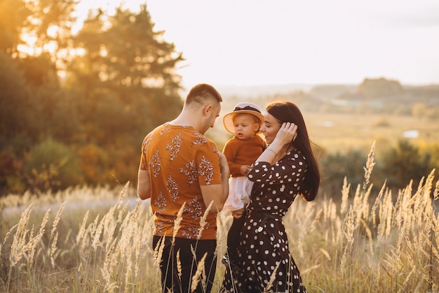 Familia con su pequeña hija en un campo de otoño