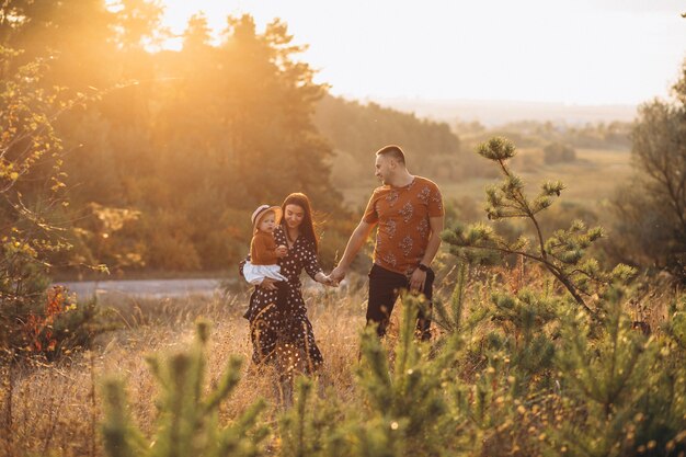 Familia con su pequeña hija en un campo de otoño