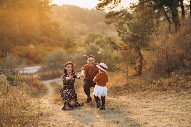 Foto gratuita familia con su pequeña hija en un campo de otoño