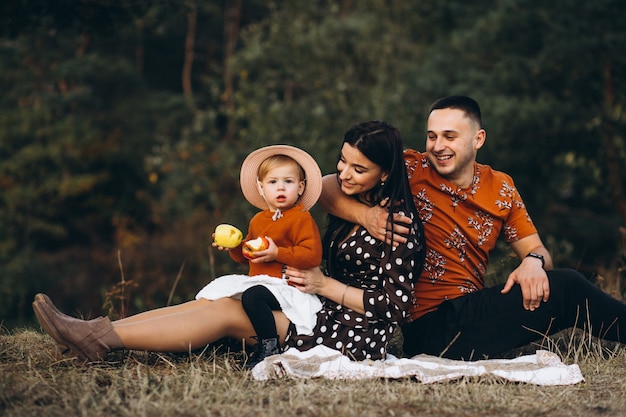 Familia con su pequeña hija haciendo un picnic en un campo