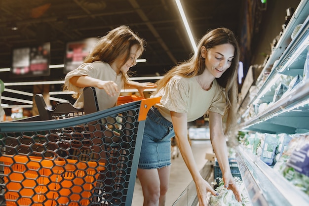 Familia en el supermercado. Mujer con camiseta marrón. La gente elige productos. Madre con hija.