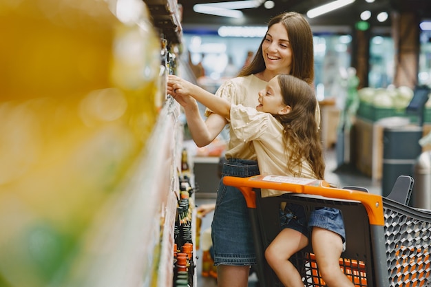 Familia en el supermercado. Mujer con camiseta marrón. La gente elige productos. Madre con hija.