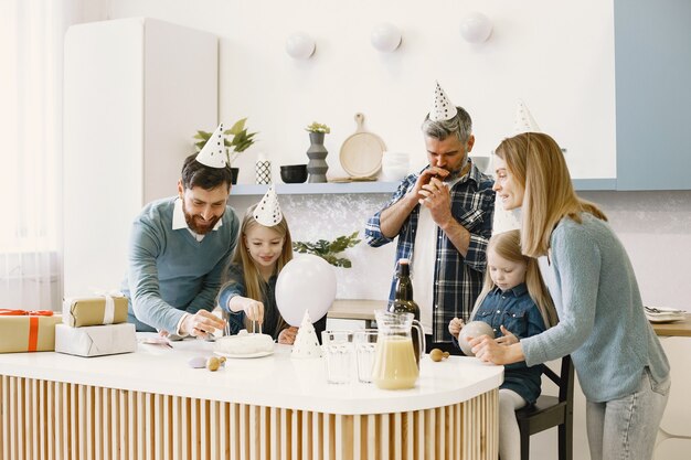 La familia y sus dos hijas tienen una celebración. Gente soplando globos. Los presentes están sobre la mesa.