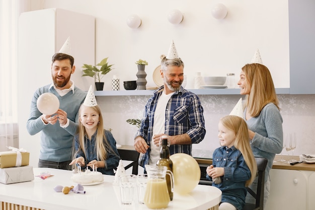 La familia y sus dos hijas tienen una celebración. Gente soplando globos. Los presentes están sobre la mesa.