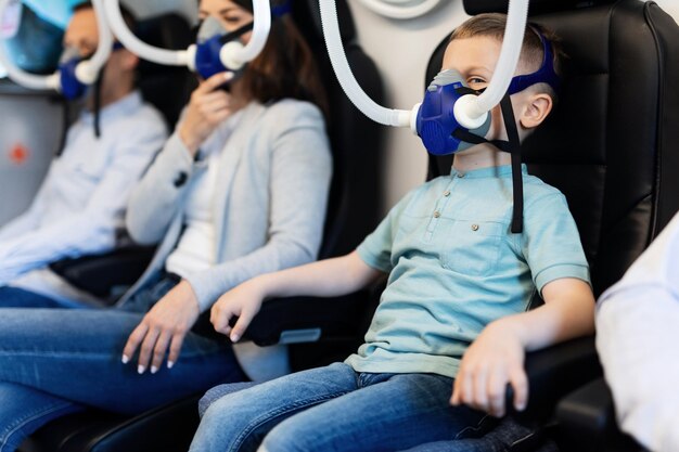 Familia con terapia en cámara hiperbárica y respirando a través de máscaras de oxígeno El foco está en el niño pequeño