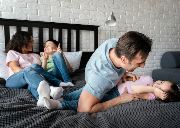 Familia de tiro completo divirtiéndose en la cama