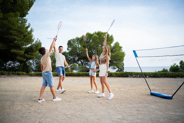 Familia de tiro completo jugando bádminton