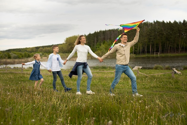 Foto gratuita familia de tiro completo jugando con cometa arcoiris