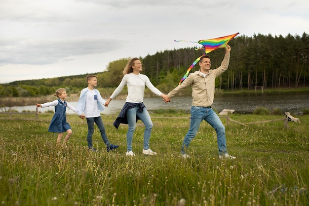 Familia de tiro completo jugando con cometa arcoiris