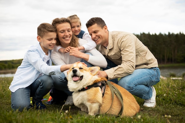 Foto gratuita familia de tiro completo con lindo perro al aire libre