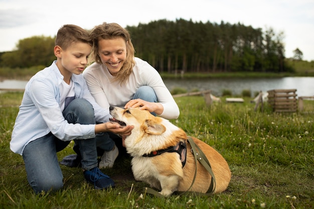 Familia de tiro completo con lindo perro en la naturaleza