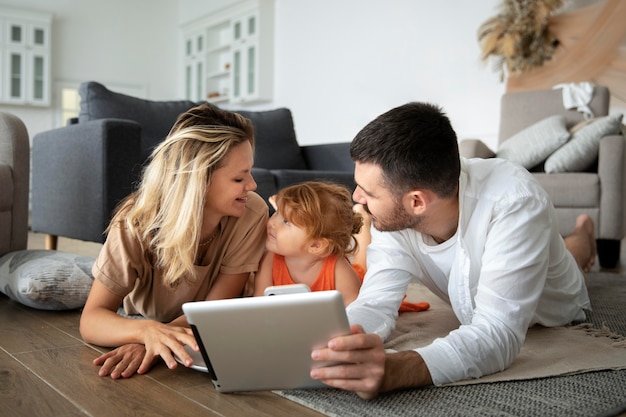 Familia de tiro completo tendido en el piso con tableta