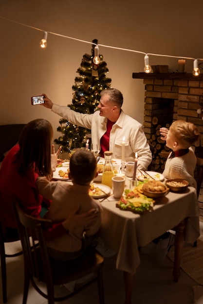 Foto gratuita familia de tiro completo tomando selfie en la mesa