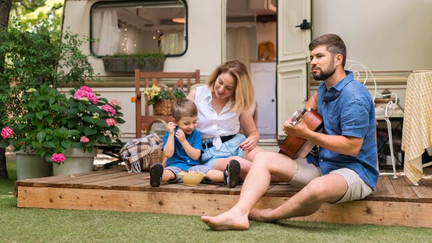 Familia de tiro largo disfrutando de música de guitarra