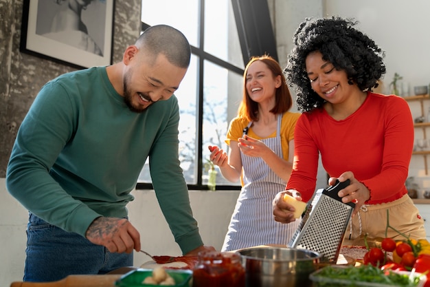 Foto gratuita familia de tiro medio cocinando deliciosa pizza