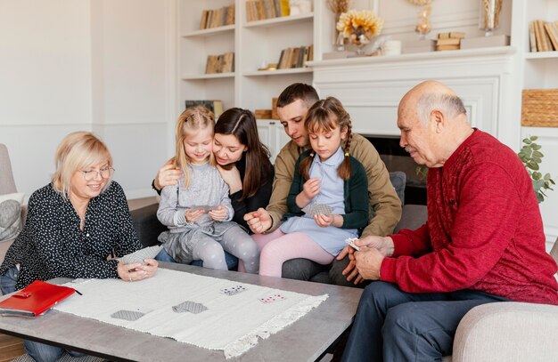 Familia de tiro medio jugando a las cartas juntos