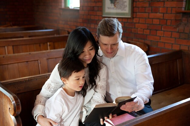 Familia de tiro medio leyendo la biblia en la iglesia