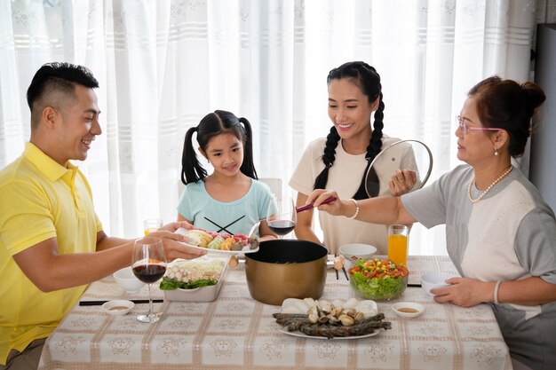 Familia de tiro medio sentado en la mesa