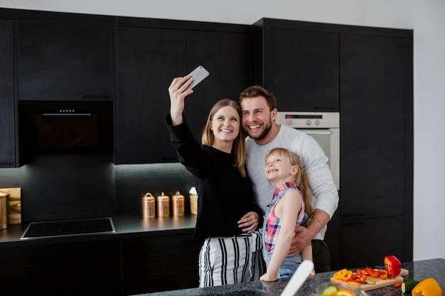 Foto gratuita familia tomando selfie en cocina