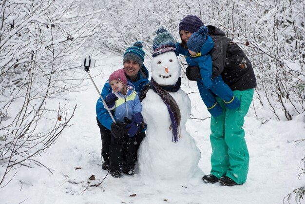 Familia tomando selfie con muñeco de nieve