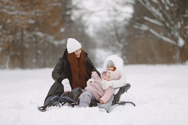 Familia en vacaciones familiares de Navidad. Mujer y niña en un parque. Personas con trineo.