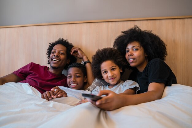 Familia viendo una película en la cama en su casa.