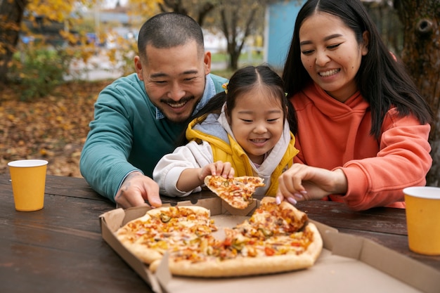 Foto gratuita familia de vista frontal con deliciosa pizza afuera