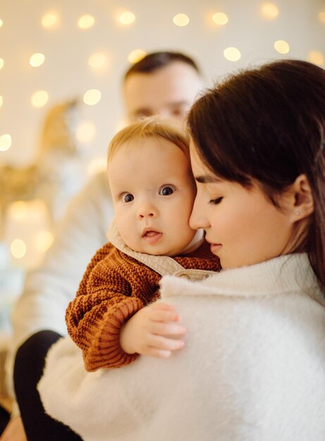 Familias retrato de feliz joven madre y padre con niño posando en el interior del hogar