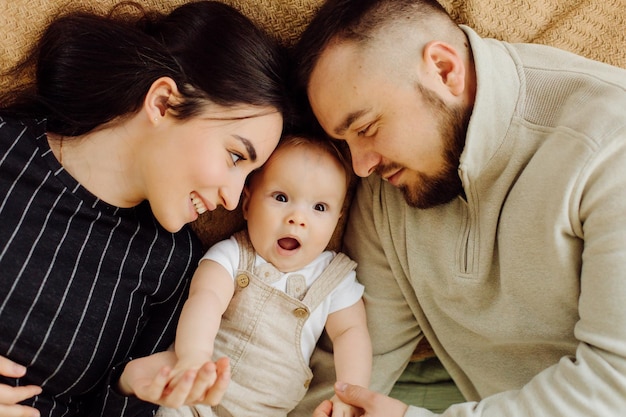 Familias retrato de feliz joven madre y padre con niño posando en el interior del hogar