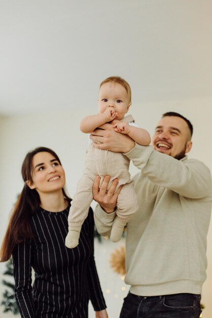 Familias retrato de feliz joven madre y padre con niño posando en el interior del hogar