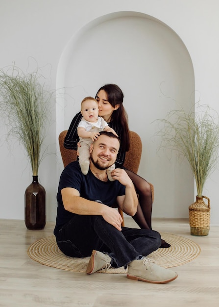 Familias retrato de feliz joven madre y padre con niño posando en el interior del hogar