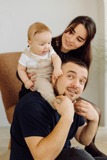 Familias retrato de feliz joven madre y padre con niño posando en el interior del hogar