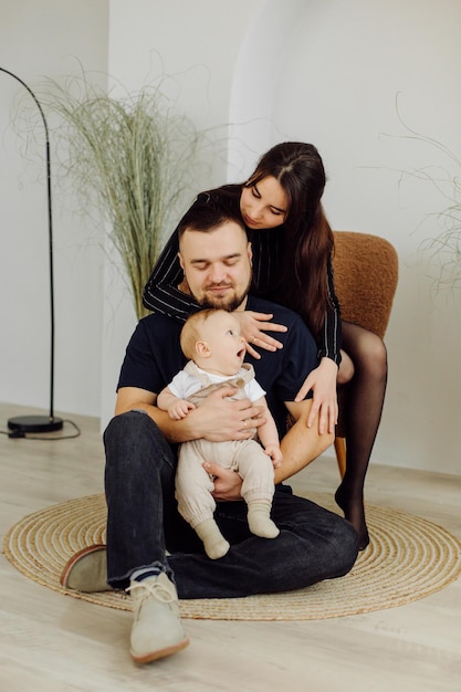 Familias retrato de feliz joven madre y padre con niño posando en el interior del hogar