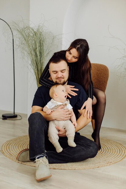 Familias retrato de feliz joven madre y padre con niño posando en el interior del hogar