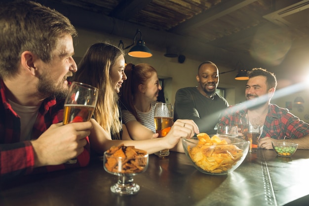 Fanáticos del deporte que animan en el bar, pub y beben cerveza mientras el campeonato, la competencia continúa