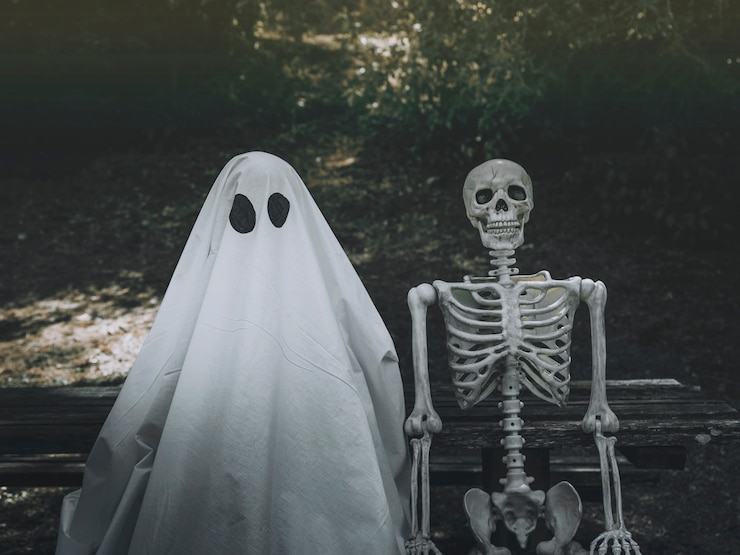 Foto gratuito fantasma y esqueleto sentado en el banco en el parque
