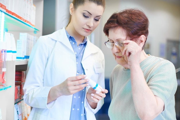 Farmacéutico ayudando a mujer adulta senior en compras