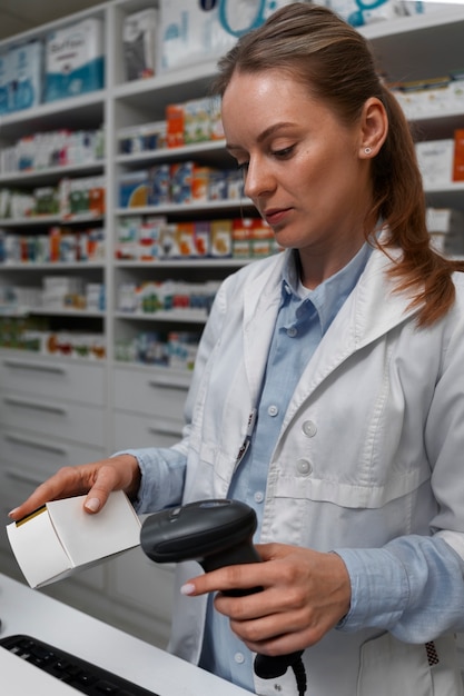 Farmacéutico femenino escaneando medicina en el mostrador